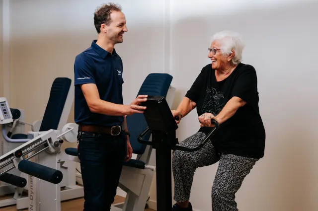 Fysiotherapie Ermelo: Fysiotherapeut stimuleert en ondersteunt de klant te bewegen op de fiets